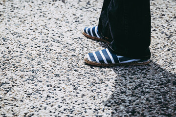 Homme dans la rue qui porte des chaussures espadrilles rayé bleu et blanc - obrazy, fototapety, plakaty