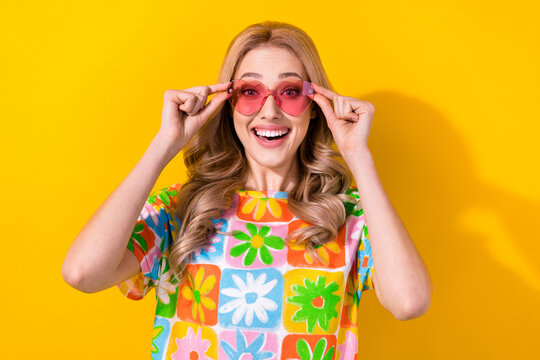 Photo of funny pretty lady try on cool sun glasses see low price shopping promo wear shirt isolated yellow bright color background