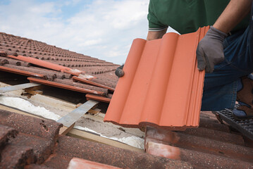 man fit in new roof shingels on the house rooftop