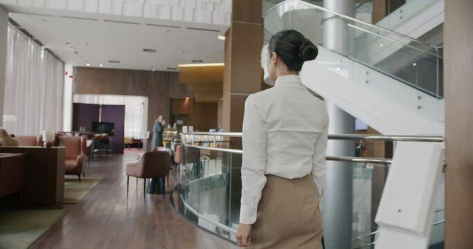 Follow shot of young Middle Eastern businesswoman walking in hotel lobby wearing formal clothing and carrying bag. People and locations concept.