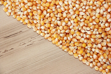 Small dry grains of corn grains on a brown wooden background