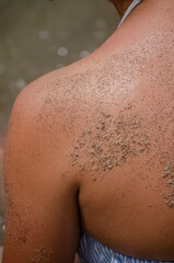 Fototapeta premium partial view of a young girl's back full of sand on the beach