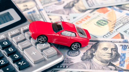 Red car on calculator on US dollar banknotes. Car financial or insurance concept. 