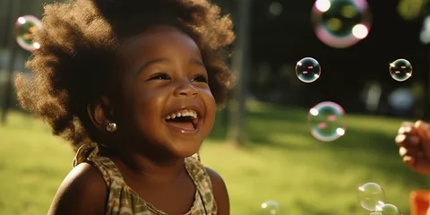 Fotobehang Afroamerikanisches Kind mit Seifenblasen und Afrolook auf der Wiese lachend mit Zähnen und hat viel Spaß, ai generativ © www.freund-foto.de