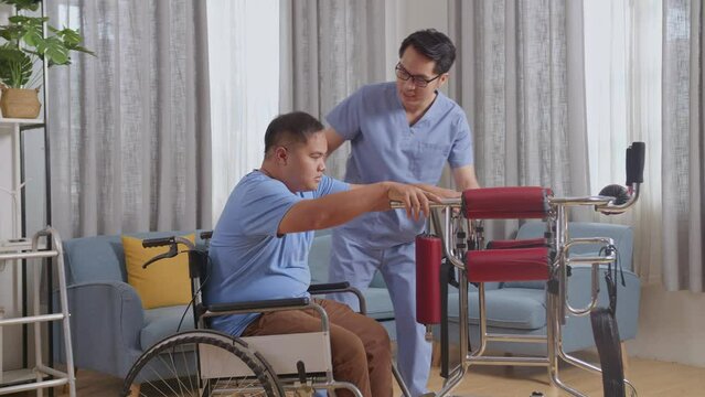 Side View Of Asian Male Nurse Helping Patient In Wheelchair Using Walker To Stand By Himself During A Physical Therapy At Home
