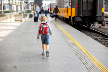 Cute preschool child with backpack, running for the train on a trainstation