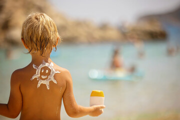Happy child, blond boy on the beach with applied sun screen,  enjoying summer, playing. Chalkidiki