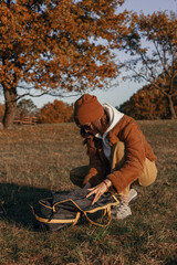 Female adventurer unpacking camping tent and getting ready for pitching on meadow in autumn forest  