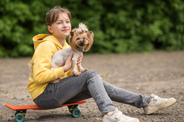 a happy child and a dog sit on a random pennyboard, a girl and a Yorkshire terrier ride a pennyboard