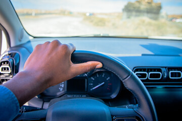 A person's hand gripping the steering wheel while in the car