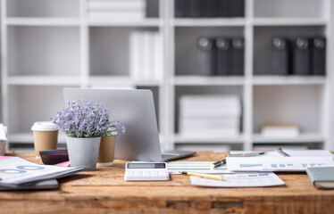 Laptop Computer, notebook, and eyeglasses sitting on a desk in a large open plan office space after working hours	