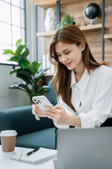 Women hand working with smart phone and laptop computer, tablet in modern home office.