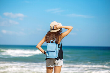 Young redhead girl in hat with bag on sea coastline on island Crete, Greece