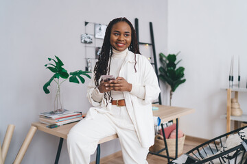 Smiling black woman with smartphone in office