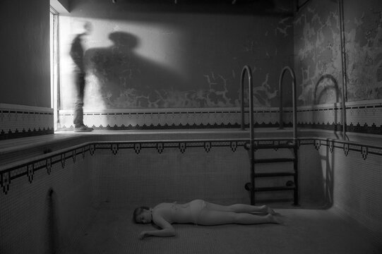 Teenage girl appears to lie dead in an empty swimming pool as a man looks on; Lincoln, Nebraska, United States of America