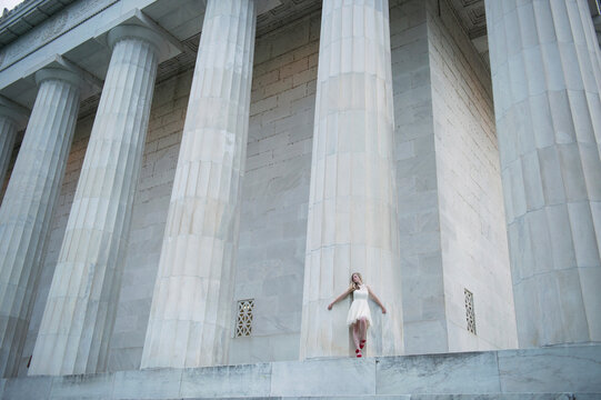 Teenage girl standing against a large column at the Lincoln Memorial in Washington DC, USA; Washington, District of Columbia, United States of America