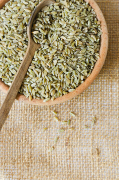 Raw freekeh or firik in a wooden bowl on burlap with a wooden spoon. Concept of healthy eating. Rustic style. Vertical orientation. Top view. Copy space