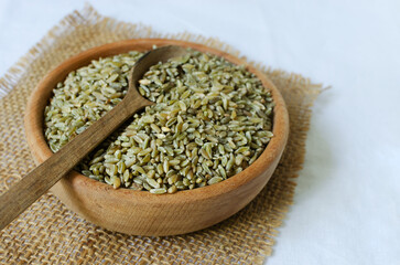Raw freekeh or firik in a wooden bowl on burlap with a wooden spoon. Concept of healthy eating. Rustic style. Vertical orientation. Top view. Selective focus.