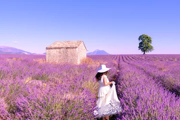 Gordijnen Une mariée habillée en blanc avec un chapeau dans un paysage magnifique, au milieu d'un champ de lavande dans le Luberon,  pendant un voyage pendant les vacances en été dans le Sud de la France © Bernard