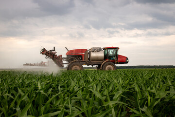 Red sprayer working in field of corn