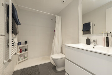 Simple modern bathroom with walk-in shower, frameless mirror on the wall, white heated towel rail and white wooden hanging cabinet