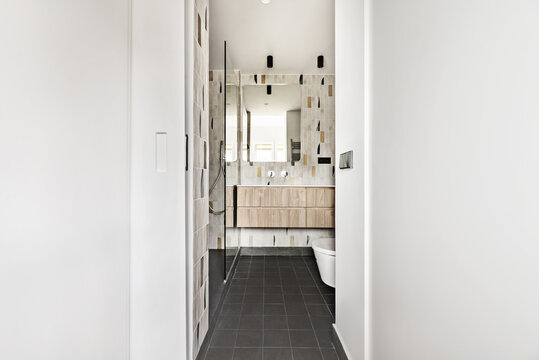 Toilet with glass partition and wooden wall units at the end of a dressing room
