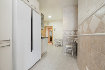An elongated kitchen with a large white two-door fridge