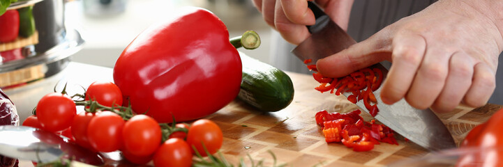 Closeup of a chef hands cutting vegetables on wooden table. Preparing vegetarian fresh vegetable salad in kitchen