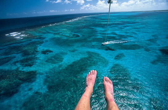 Man's legs and feet suspended above a reef in the Caribbean while parasailing; Turks and Caicos Islands, West Indies