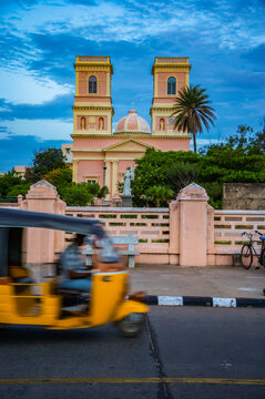 Auto rickshaw on a road in Pondicherry, India, travelling on a street passing by a church building; Pondicherry, Tamil Nadu, India
