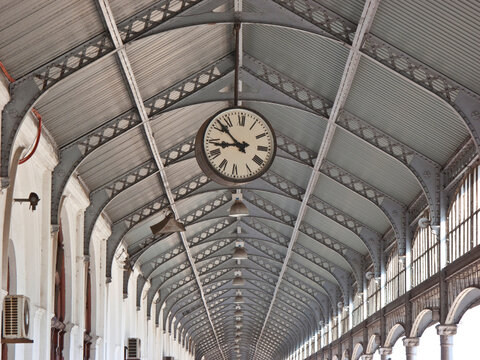 Clock hanging from the rafters of a ceiling; Maputo, Mozambique
