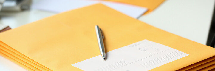 Yellow envelope with business correspondence with pen on desktop in office. Sending bank notices...