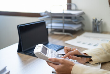 Fototapeta premium Asian female accountant or banker making calculations. Savings, finances and economy concept through a laptop.