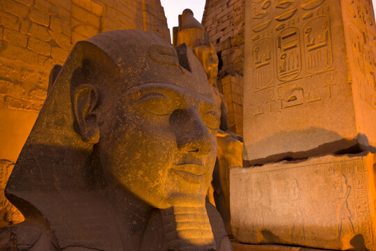 Stone head of Ramses II illuminated at night in Luxor Temple; Luxor, Egypt
