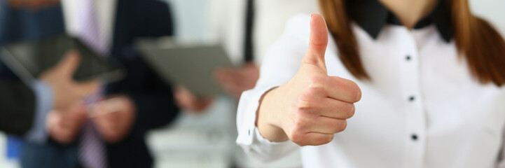 Businessman holds thumbs up in background are business partners. Recommendation of business consultant and quality company development services