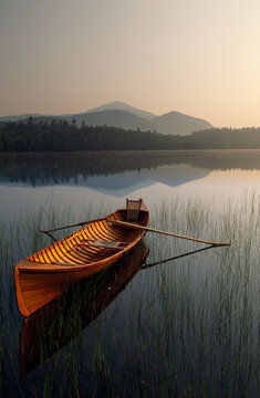 Boat with oars floating on a tranquil lake a twilight in Adirondack Park, New York, USA; New York, United States of America