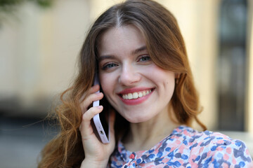 Close-up portrait of a smiling girl talking on a smartphone.