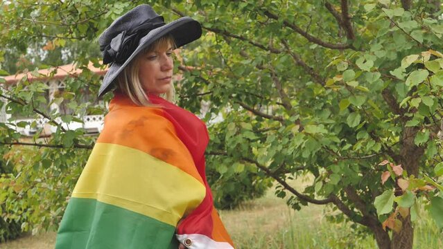 A woman with an LGBT flag on her face. Young crying woman with LGBT flag on her cheek. The concept of violation of the rights and equality of LGBT persons. A young woman with short hair covering part 