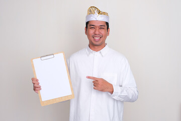 Balinese man smiling and pointing to empty white paper on a clipboard