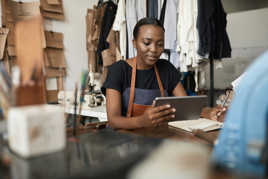 Young African female leather worker using a digital tablet - Powered by Adobe