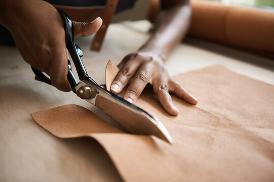 African female artisan cutting leather in her workshop