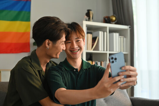 Asian teens gay couple using phone camera and taking a selfie together, LGBT lifestyle concept.