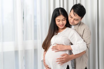 Fototapeta premium husband and wife pregnant standing by the window waiting for the baby to be born happily