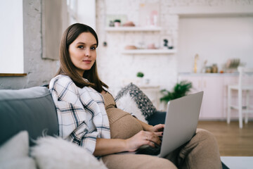 Young pregnant woman working on laptop in living room