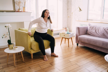 Pregnant woman doing special exercise in armchair at home