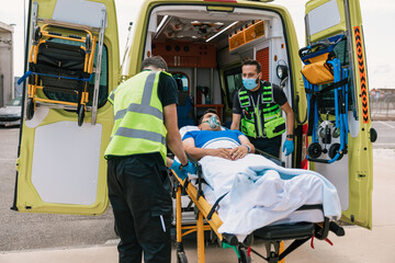 Emergency medical technicians taking patient away in automobile