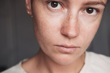 Close up portrait of a young woman with sad eyes, looking seriously at the camera 