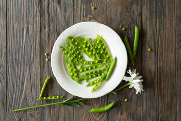 Fototapeta na wymiar Fresh green peas on a wooden background. Summer crop of peas.