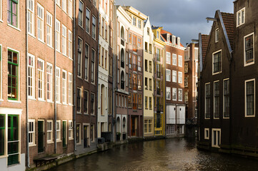Fototapeta na wymiar Sunlit facades of houses in Amsterdam separated by a canal