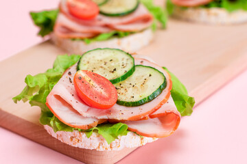 Light Breakfast. Quick and Healthy Sandwiches. Rice Cakes with Ham, Tomato, Fresh Cucumber and Green Salad on Wooden Cutting Board